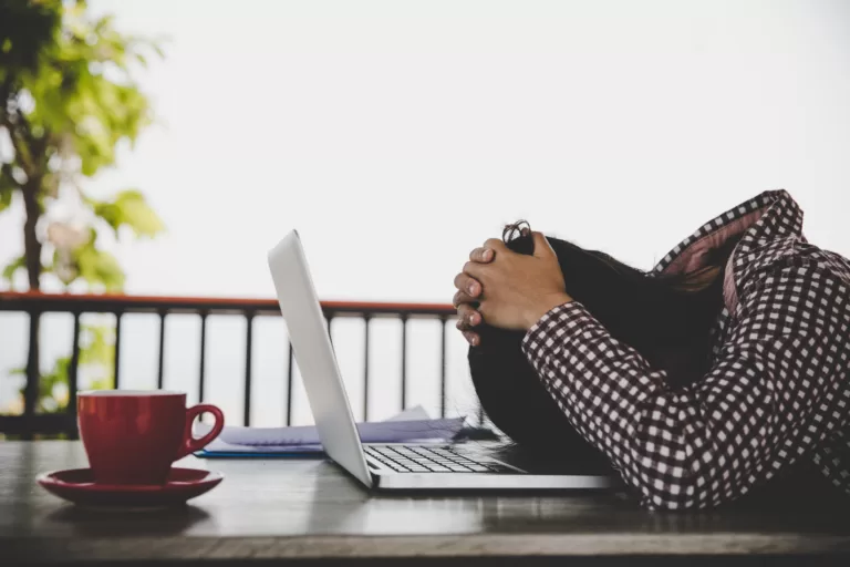 woman feeling burnt out and leaning on her computer