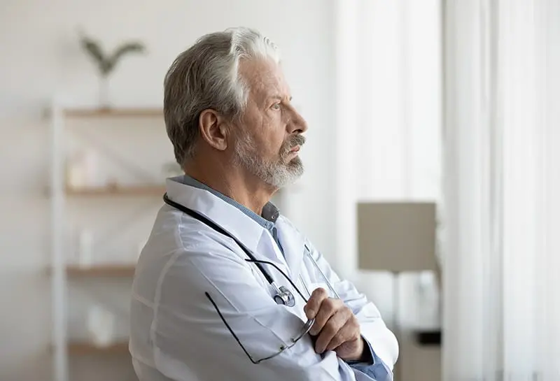 Caduceus group doctor looking out a window in contemplation